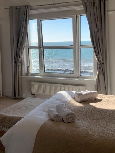 a bedroom with two towels on a bed with a window at Beach View - A Truly Stunning House Opposite The Sea! Sleeps 10! Families, Friends, Contractors and Pets are all Welcome! in Sandgate