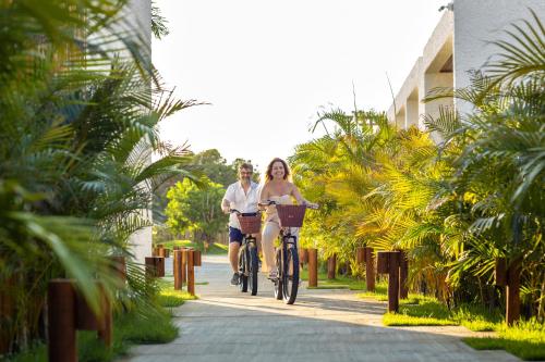 a man and a woman riding a bike down a sidewalk at Nanii Hotel in São Miguel do Gostoso