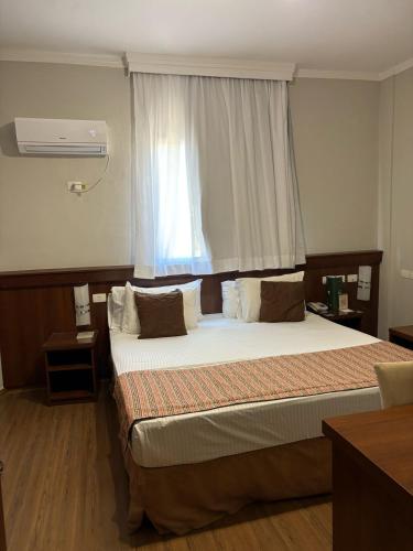 a bedroom with a large bed in front of a window at Class Hotel Passos in Passos