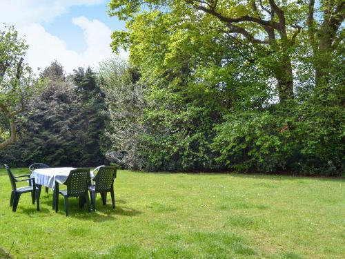 a table and chairs in a field with trees at Yew Tree Cottage in Arford