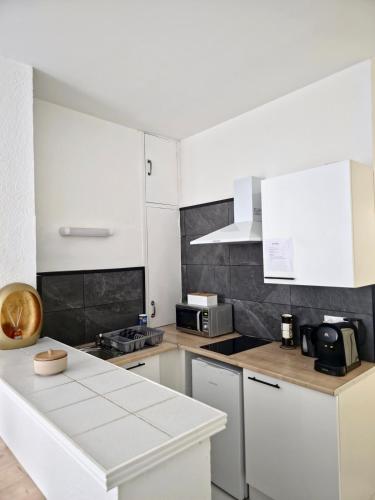 une cuisine avec des placards blancs et un comptoir blanc dans l'établissement Tour Est - T2 entre Cité Médiévale et Bastide, à Carcassonne