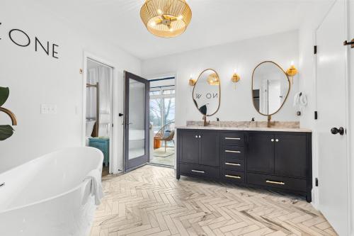 a bathroom with a tub and a sink and two mirrors at Otherside of Paradise in Mooresville