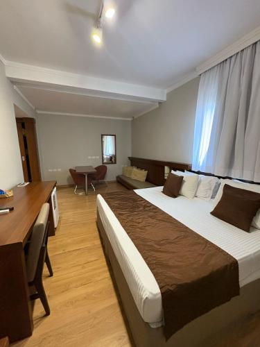 a hotel room with a large bed and a desk at Class Hotel Passos in Passos