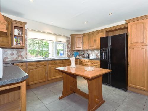 eine Küche mit Holzschränken und einem schwarzen Kühlschrank in der Unterkunft Oaklands in Langrigg