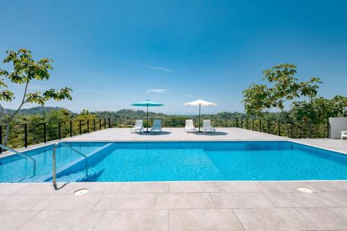 a swimming pool with two chairs and umbrellas at Tardes Doradas in Quepos