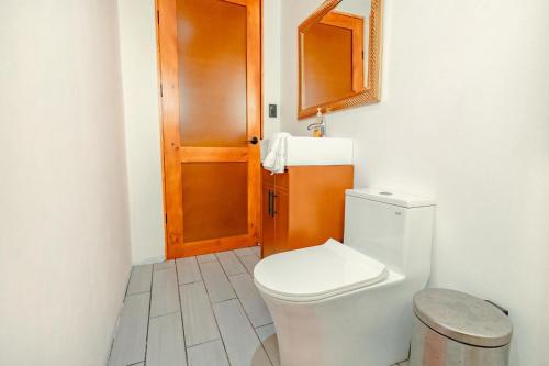a bathroom with a toilet and a wooden door at Tardes Doradas in Quepos