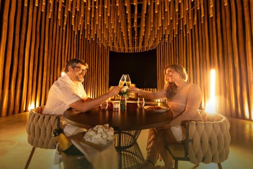 a man and woman sitting at a table with wine glasses at Nanii Hotel in São Miguel do Gostoso