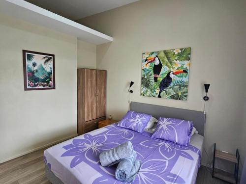 a bedroom with a purple bed with two pictures on the wall at F2 PAPEETE CITY CENTER in Papeete
