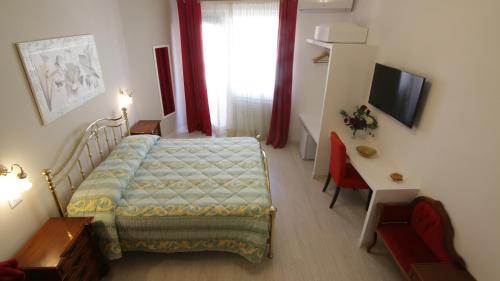 una camera con letto, scrivania e TV di B&B La Perla di Roma a Roma