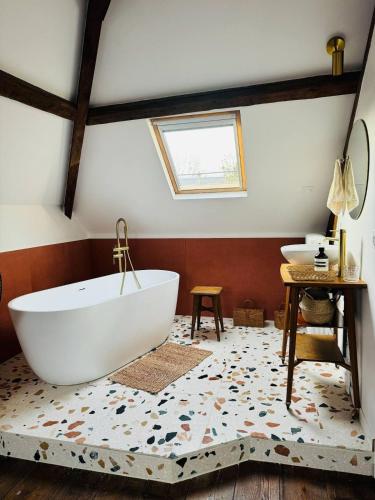 La salle de bains est pourvue d'une grande baignoire blanche. dans l'établissement Maison de maitre normande Etretat et Honfleur, à Bolbec