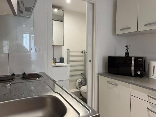 une cuisine avec un évier et un micro-ondes dans l'établissement Studio équipé confort proche de toutes commodités, à La Seyne-sur-Mer