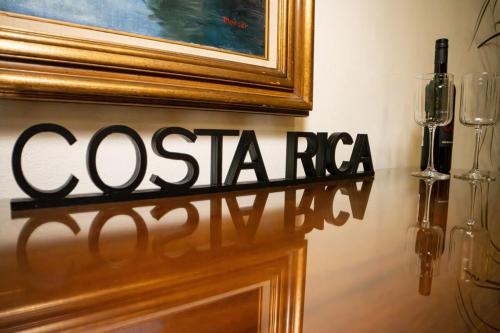 a sign on a wall with a painting and wine glasses at Jungle Bungalow at Oropel Lodge in Puerto Viejo