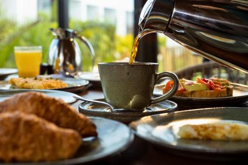a cup of coffee on a table with plates of food at Nanii Hotel in São Miguel do Gostoso