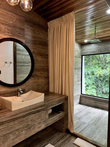 a bathroom with a sink and a mirror and a window at Jungle Bungalow at Oropel Lodge in Puerto Viejo