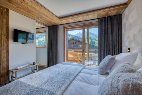 une chambre avec un lit et une grande fenêtre dans l'établissement Les Chalets de La Clusaz - Appartement Le Faon, à La Clusaz