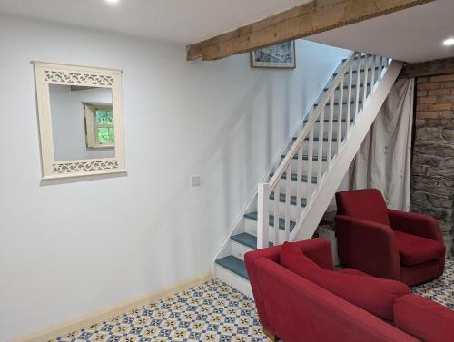 a living room with two red chairs and a staircase at Herdsmans Cottage in Slane