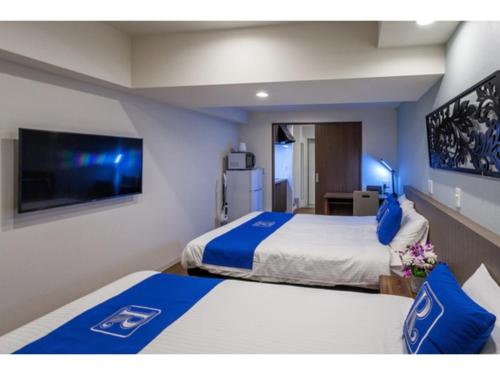 a hotel room with two beds and a flat screen tv at Condominium Resort Naha Living Inn Asahibashiekima - Vacation STAY 92450v in Naha