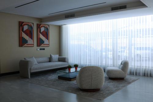a living room with a couch and chairs and a large window at BHomed Shaab in Kuwait