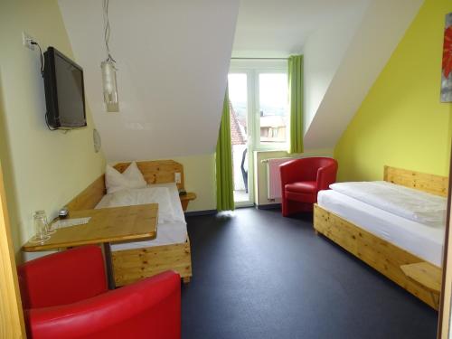 a room with two beds and a desk and a tv at Hotel Demling in Randersacker