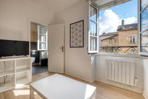 un salon avec une télévision et une grande fenêtre dans l'établissement Le deuxième ciel de la vertu, à Périgueux