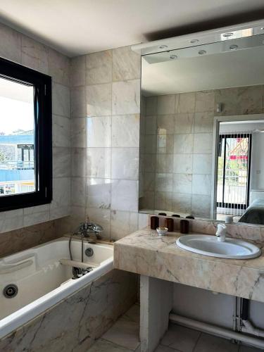 une salle de bain avec un lavabo, une baignoire et un miroir dans l'établissement Résidence Louisiane - Arcachon: T3 moderne à deux pas de la plage MAE-5221, à Arcachon