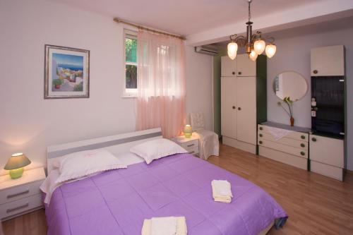 a bedroom with a purple bed and a mirror at Guest house with garden - Zuvan in Split