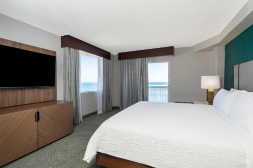 a hotel room with a bed and a flat screen tv at Holiday Inn Hotel & Suites Daytona Beach On The Ocean by IHG in Daytona Beach