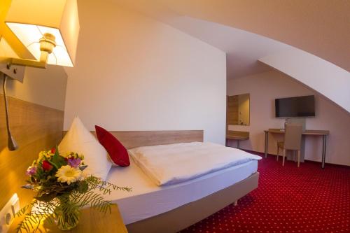 una habitación de hotel con una cama y una mesa con flores en Hotel Restaurant Bären en Isny im Allgäu