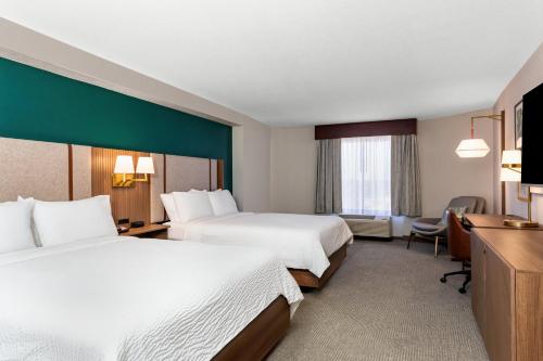 a hotel room with two beds and a desk at Holiday Inn Hotel & Suites Daytona Beach On The Ocean by IHG in Daytona Beach