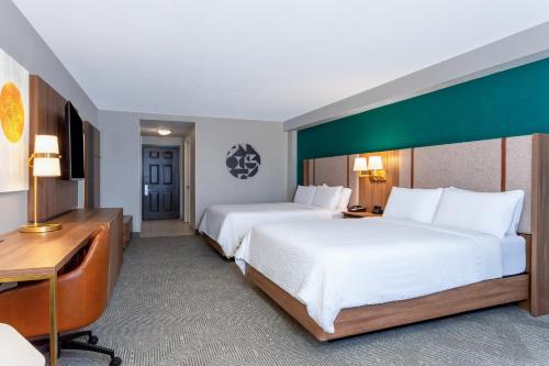 a hotel room with two beds and a desk at Holiday Inn Hotel & Suites Daytona Beach On The Ocean by IHG in Daytona Beach