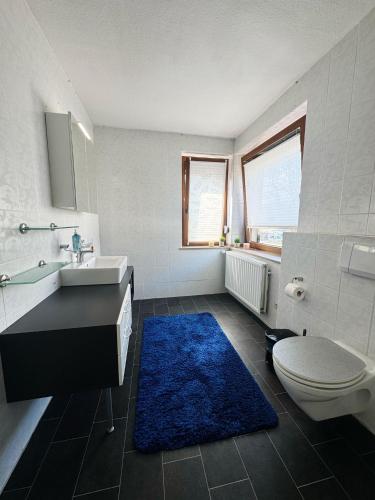 a bathroom with a sink and a toilet and a blue rug at Geräumiges Haus im Herzen Jülichs in Jülich