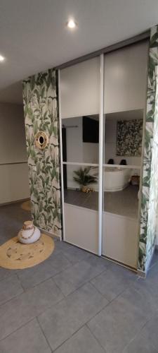 une chambre avec des portes coulissantes en verre et une chambre avec une baignoire dans l'établissement Ô Jardin d'Eden, à Gigean
