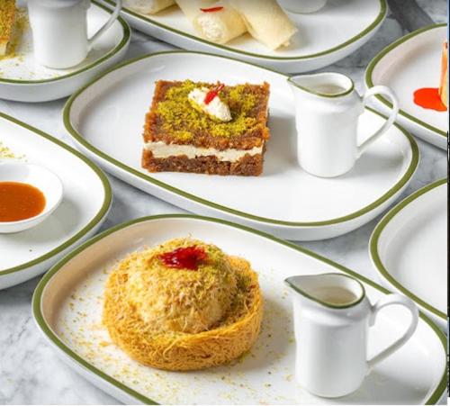 a table with plates of food with a piece of cake at BHomed Shaab in Kuwait