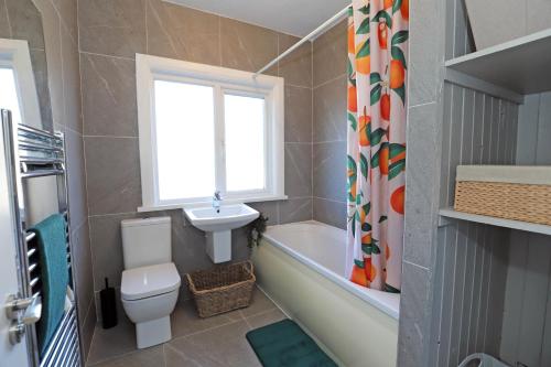 a bathroom with a toilet and a sink and a tub at Lisburn Townhouse in Lisburn