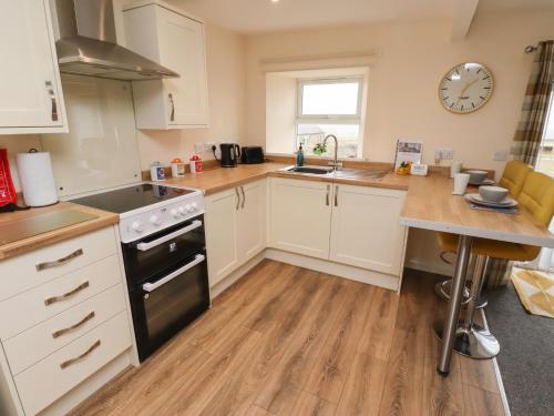 a kitchen with white cabinets and a black stove top oven at Henhill Lodge in Chathill