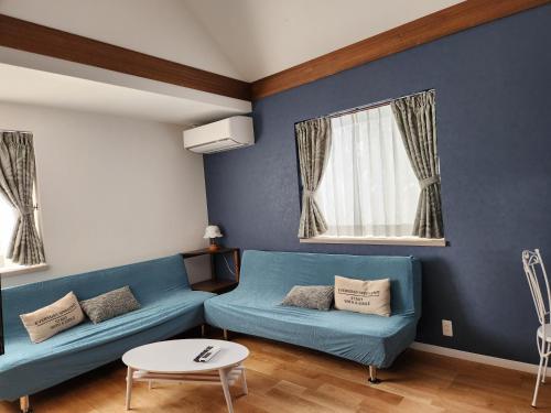 a living room with two blue couches and a table at Pension Green Lake in Gujo