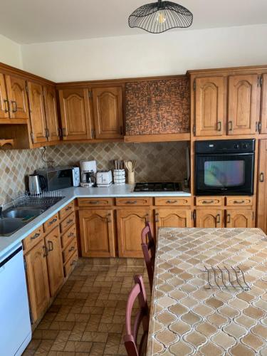 a kitchen with wooden cabinets and a table with a table sidx sidx at GITE du Petit Maine in Pontmain
