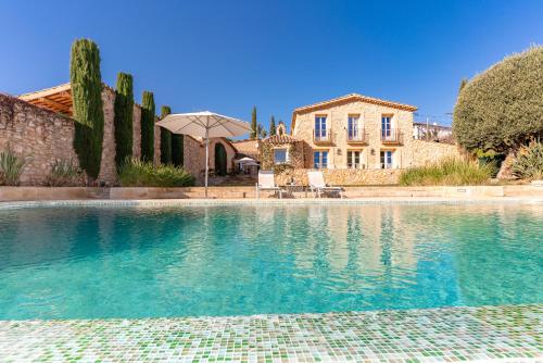 a large swimming pool in front of a house at Casa de Piedra ubicada en el exclusivo wine village de Viladellops, te ofrece una experiencia única, donde el lujo y la tradición se fusionan en un entorno natural privilegiado in Viladellops