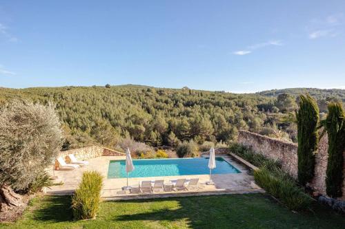 a swimming pool in a yard with chairs and trees at Casa de Piedra ubicada en el exclusivo wine village de Viladellops, te ofrece una experiencia única, donde el lujo y la tradición se fusionan en un entorno natural privilegiado in Viladellops