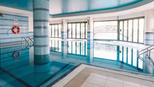 a swimming pool in a building with a view of the water at Holiday Inn Algarve Albufeira by IHG in Albufeira