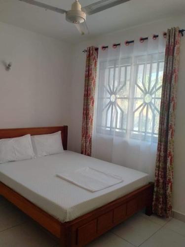 a bedroom with a bed and a window with curtains at R&Joy Stays in Mtwapa