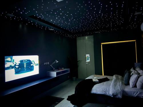a bedroom with a bed and a television with stars on the ceiling at Starlit By Zameen Opal in Lahore