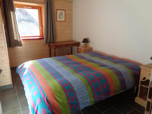 - une chambre avec un lit et une couverture colorée dans l'établissement Appartement de plain pied dans chalet, à Saint-Sorlin-dʼArves