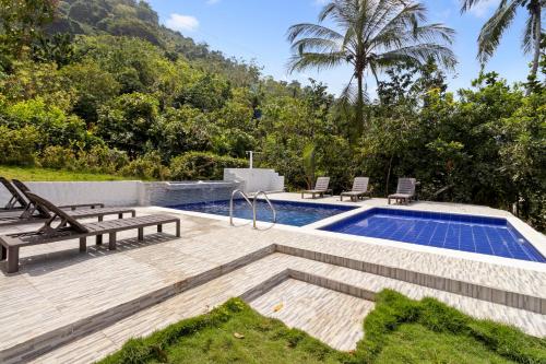 a swimming pool with two lounge chairs next to at Hostal Casa del Rio in Guachaca