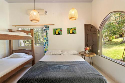two beds in a room with a window at Hostal Casa del Rio in Guachaca