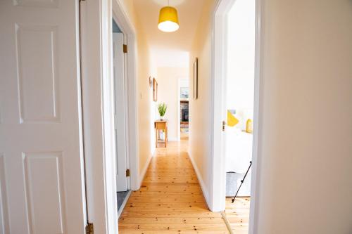 a hallway with a hard wood floor and a white door at Wild Atlantic Way Retreat by Shortstays in Ballynahown