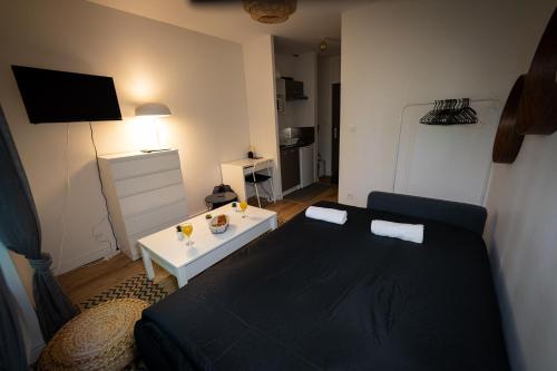- une chambre avec un lit noir et une table blanche dans l'établissement Le Petit Brienne - Centre-Ville Aéroport TBS, à Toulouse