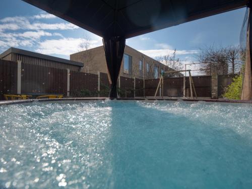 una grande piscina d'acqua con ombrellone di Cambridge - hot tub, sauna, parking, pool table a Trumpington