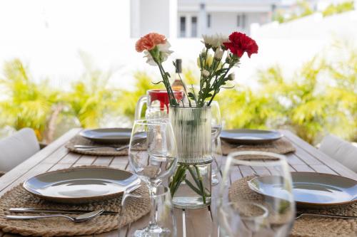 a wooden table with plates and flowers in a vase at Luxe nieuwbouw villa toplocatie in Jan Thiel in Jan Thiel