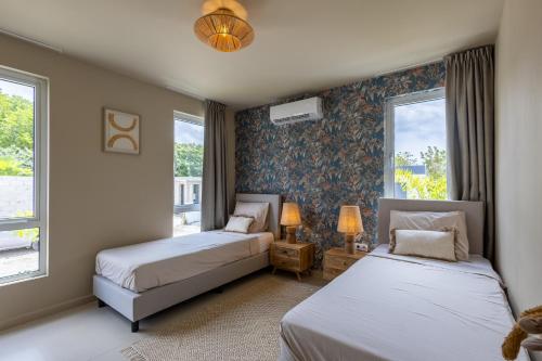 two beds in a room with two windows at Luxe nieuwbouw villa toplocatie in Jan Thiel in Jan Thiel